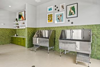 Two stainless steel sinks are installed in a green and white tiled wall.